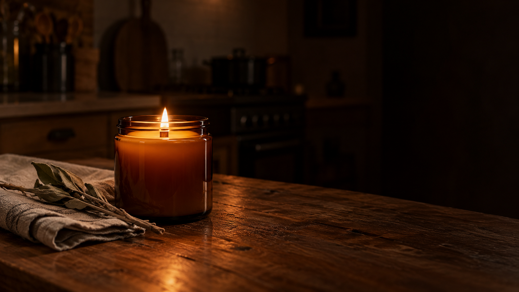 The same amber jar candle lit in the evening, glowing on a dark oak kitchen counter